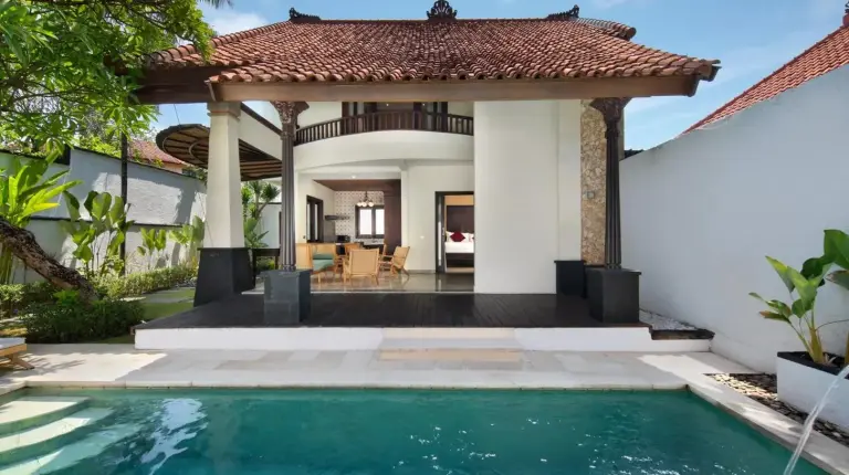 a swimming pool with a wooden deck next to a house at The Club Villas Seminyak in Seminyak