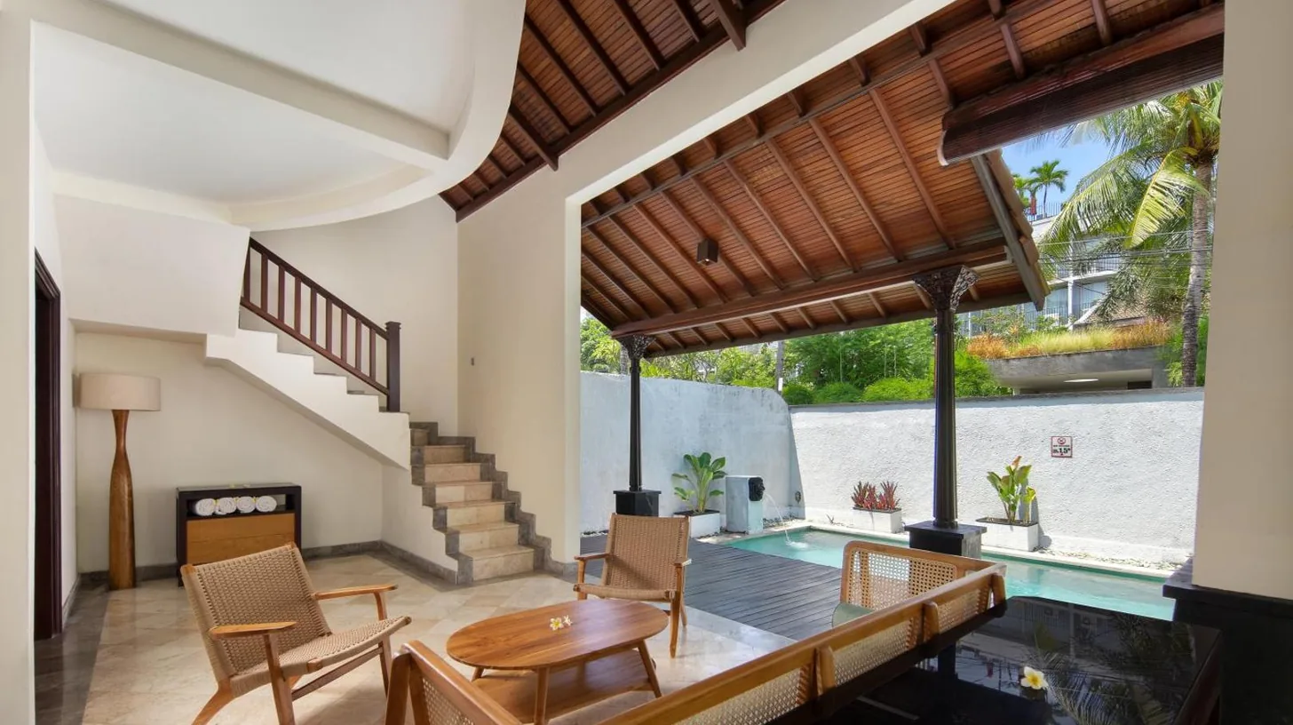 an open living room with a staircase and a table and chairs at The Club Villas Seminyak in Seminyak