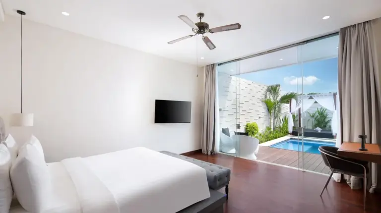 a white bedroom with a bed and a desk and a window at The Daha Luxury Villas in Seminyak