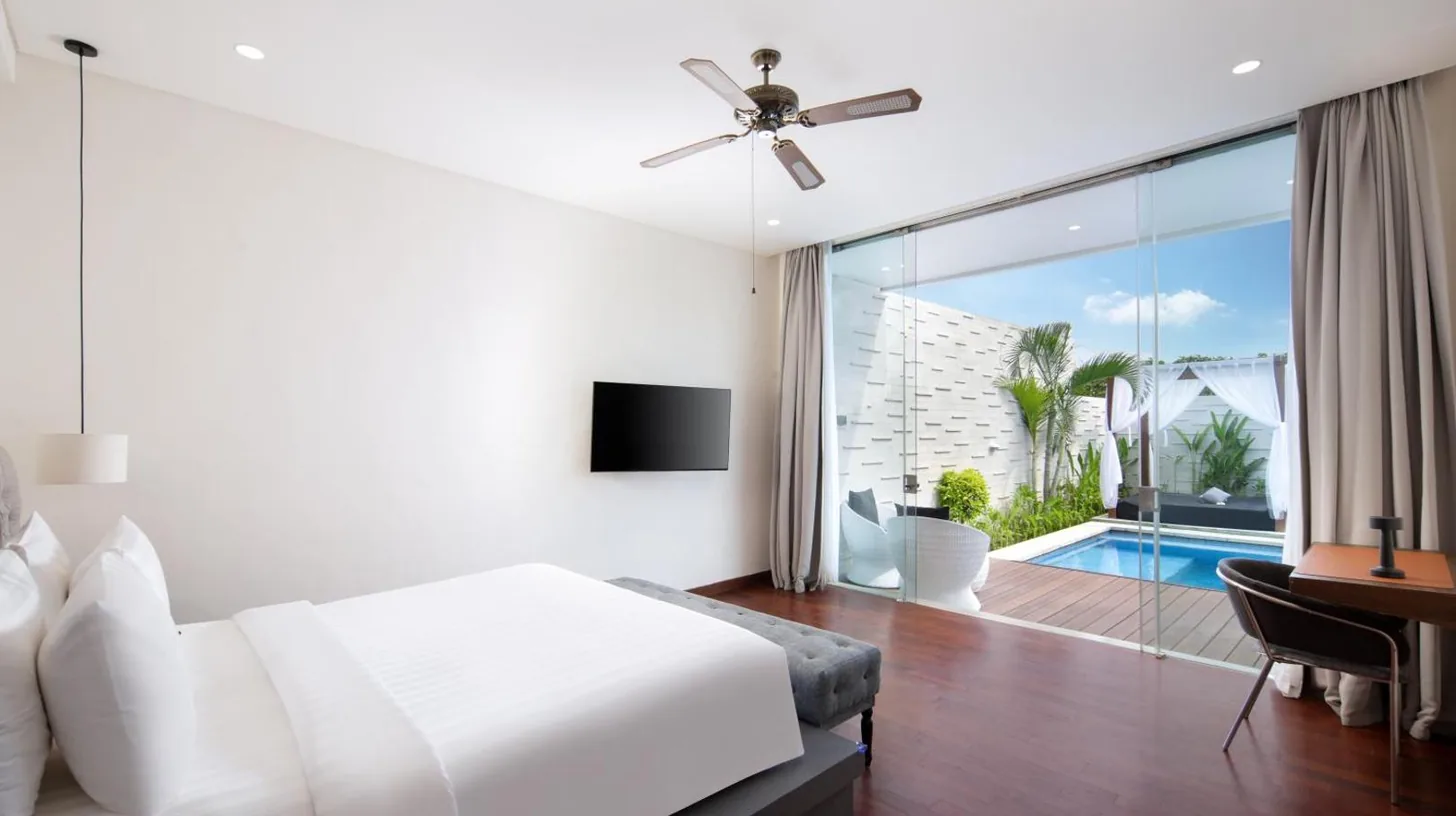 a white bedroom with a bed and a desk and a window at The Daha Luxury Villas in Seminyak