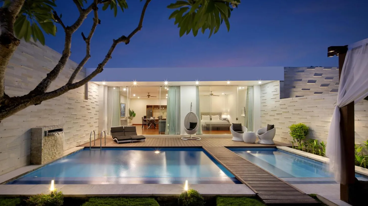 a swimming pool with chairs next to a house at The Daha Luxury Villas in Seminyak