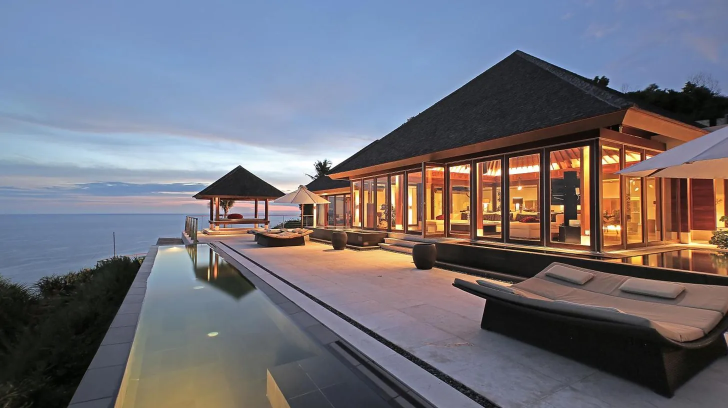 a house with a swimming pool next to the water at The Edge Bali in Uluwatu