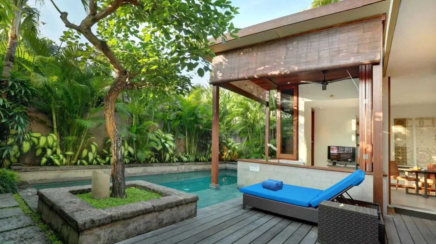 ein Hinterhof mit einem Pool und einer Holzterrasse im The Elysian Boutique Villa Hotel in Seminyak