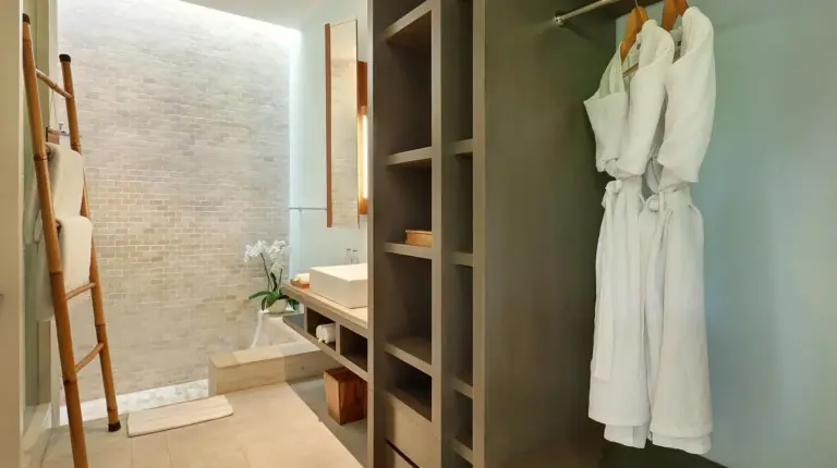 ein Badezimmer mit einem begehbaren Kleiderschrank und weißen Kleidungsstücken im The Elysian Boutique Villa Hotel in Seminyak