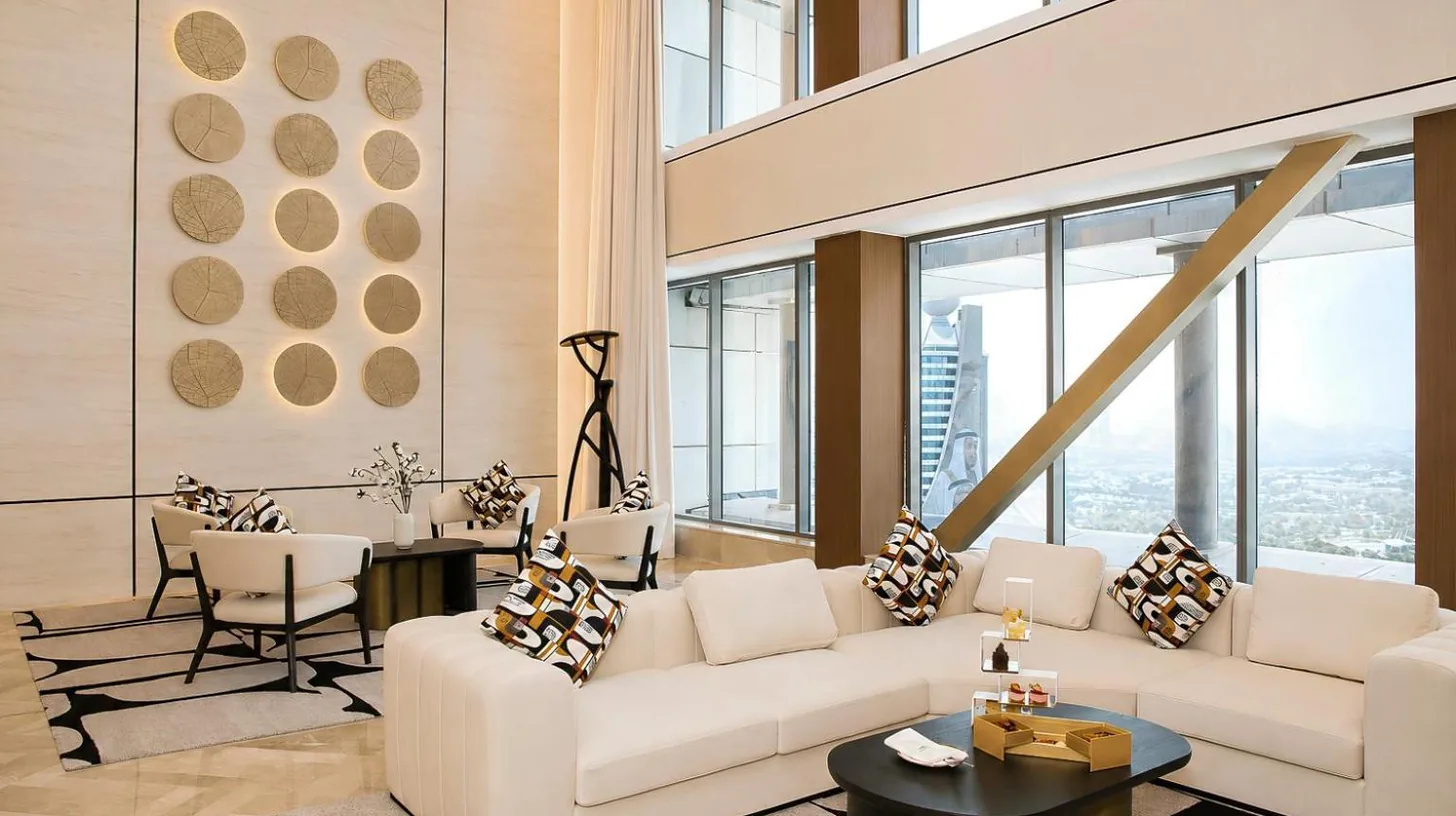 un salon avec mobilier blanc et grandes fenêtres au The H Dubai à Dubaï