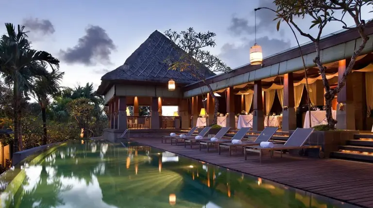 a resort with a swimming pool and lounge chairs at The Kayana in Seminyak