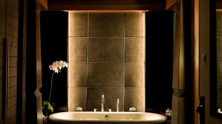 a bathroom with a bath tub with a mirror at The Kayana in Seminyak