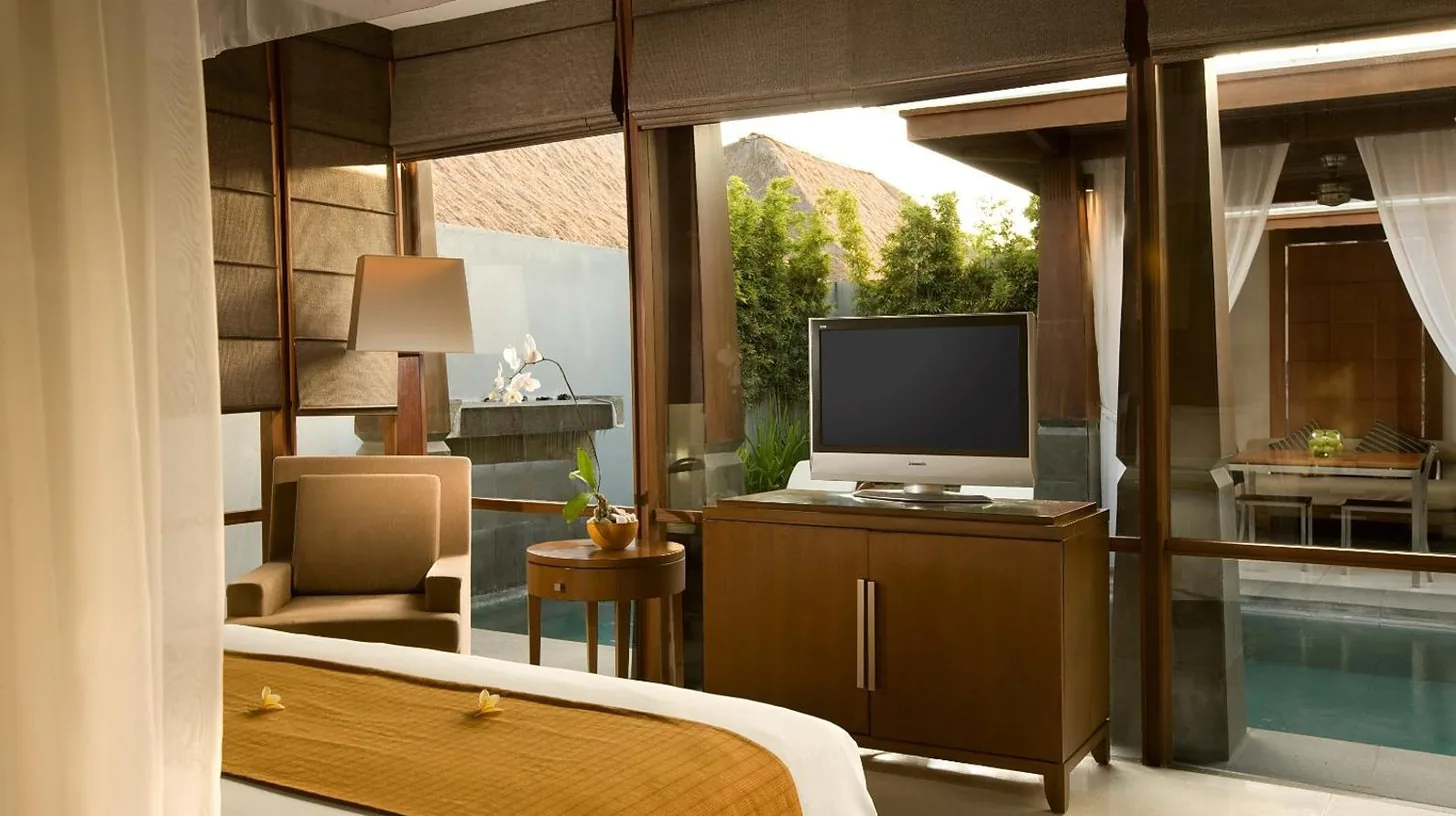 a bedroom with a television and a room with a pool at The Kayana in Seminyak