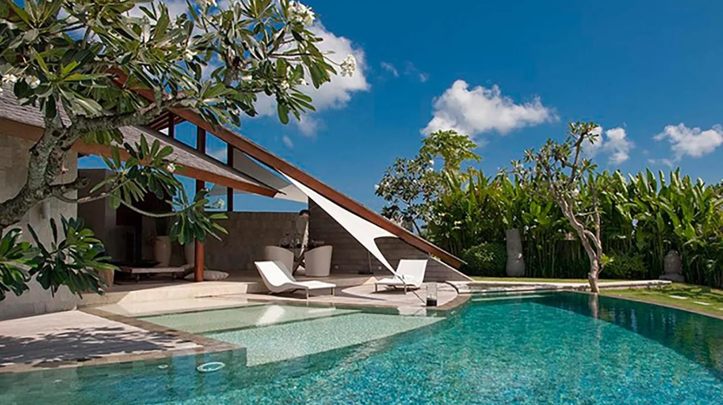 a swimming pool with two lounge chairs next to a house at The Layar - Designer Villas and Spa in Seminyak