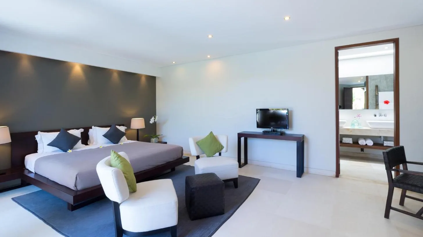 a bedroom with a bed and chairs and a television at The Layar - Designer Villas and Spa in Seminyak