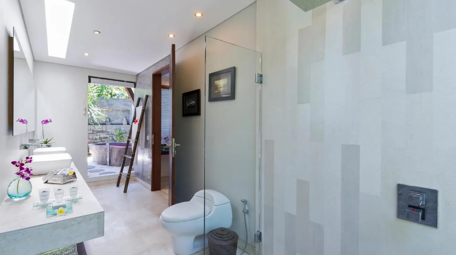 a woman laying on a rock with pink flowers at The Layar - Designer Villas and Spa in Seminyak