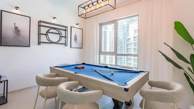 a living room with a pool table and chairs at the 'New York' Condo - 4BR Executive Burj Khalifa Suite in Dubai