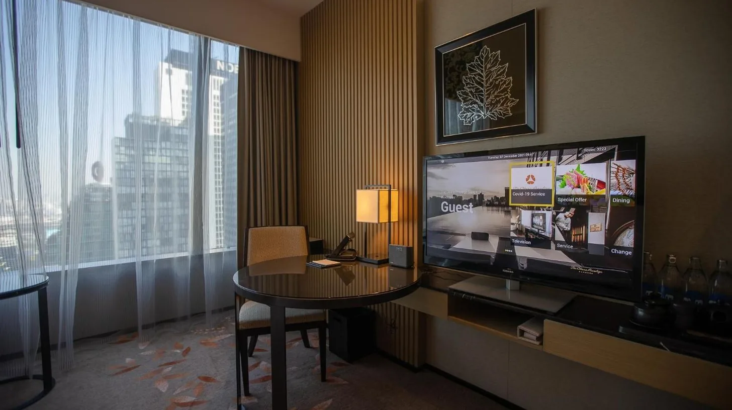 a hotel room with a table and a large television at The Okura Prestige Bangkok in Bangkok