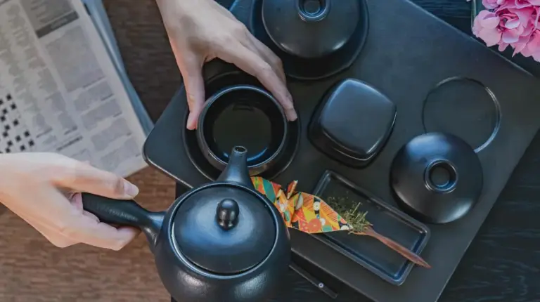 a person holding a tea pot on a table at The Okura Prestige Bangkok in Bangkok