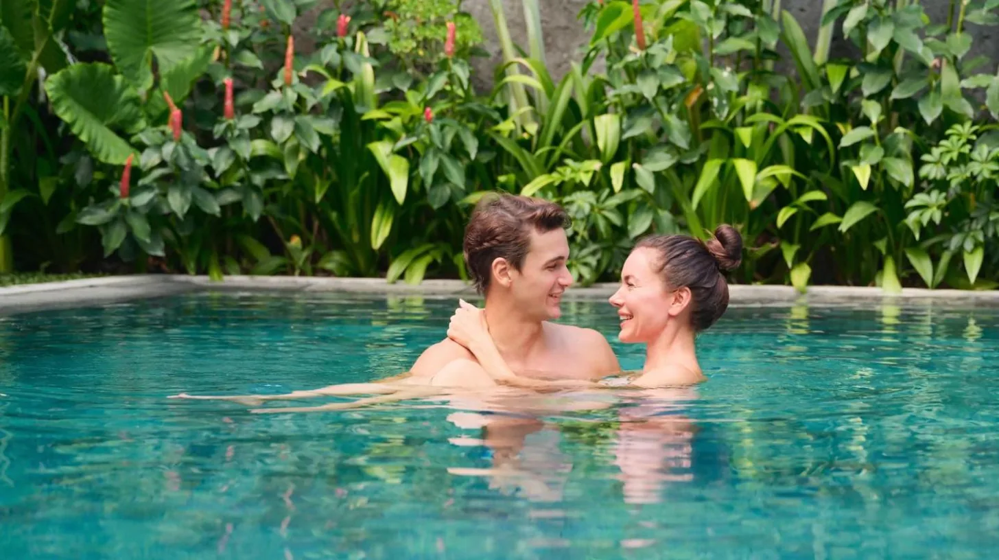 a man and woman swimming in a swimming pool at The One Boutique Villa & Spa Seminyak in Seminyak