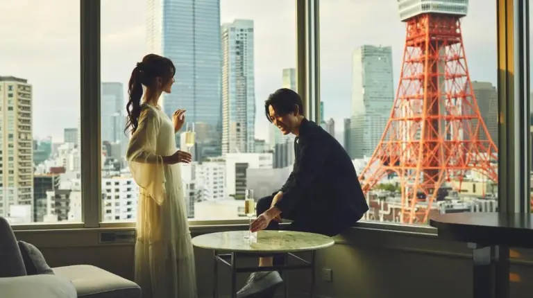 a man and a woman sitting at a table in a window at The Prince Park Tower Tokyo - Preferred Hotels & Resorts