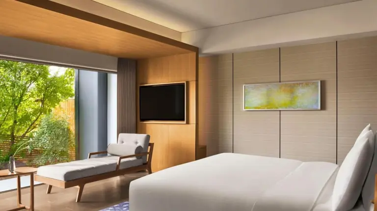 a bedroom with a white bed and a chair and a television at The Ritz-Carlton Kyoto in Kyoto