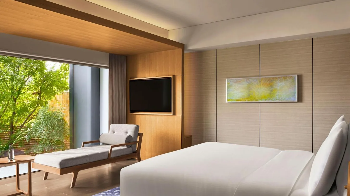 a bedroom with a white bed and a chair and a television at The Ritz-Carlton Kyoto in Kyoto