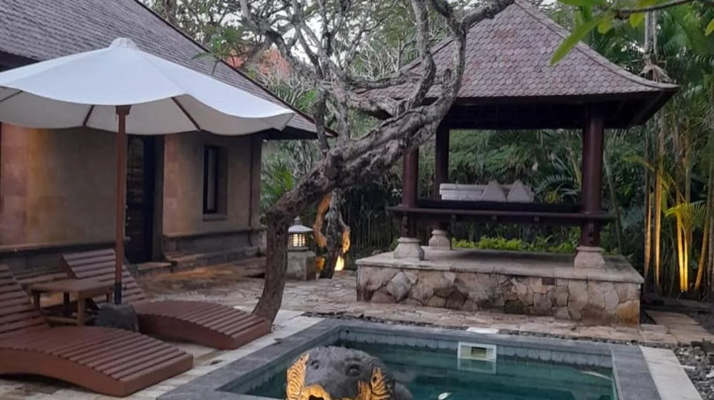 a swimming pool with a statue next to a house at The Royal Beach Seminyak Bali in Seminyak