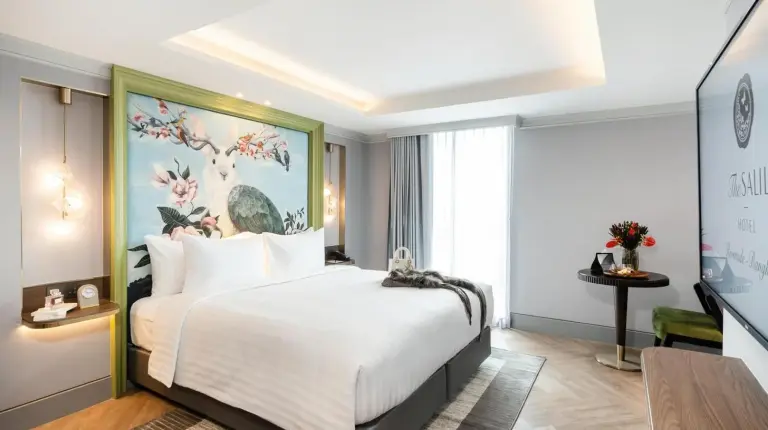 a bedroom with a large bed with a painting on the wall at The Salil Hotel Riverside Bangkok in Bangkok
