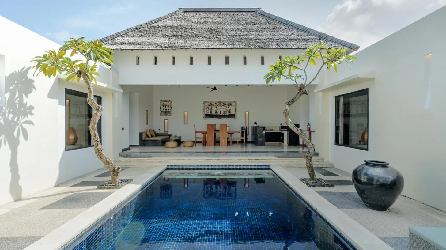 a villa with a swimming pool and a house at The Seminyak Suites Private Villas in Seminyak