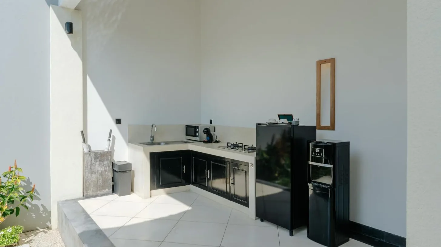a kitchen with black appliances and white tile floors at The Seminyak Suites Private Villas in Seminyak