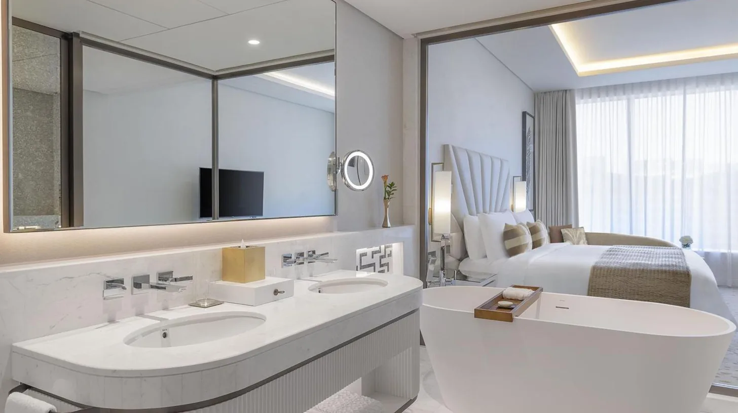 a white bedroom with a large bed and a bathroom at The St. Regis Dubai