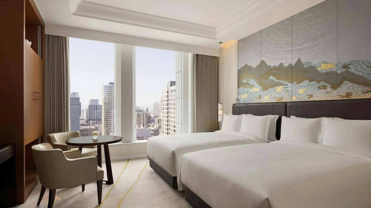 a hotel room with two beds and a table and a window at The St. Regis Osaka in Osaka