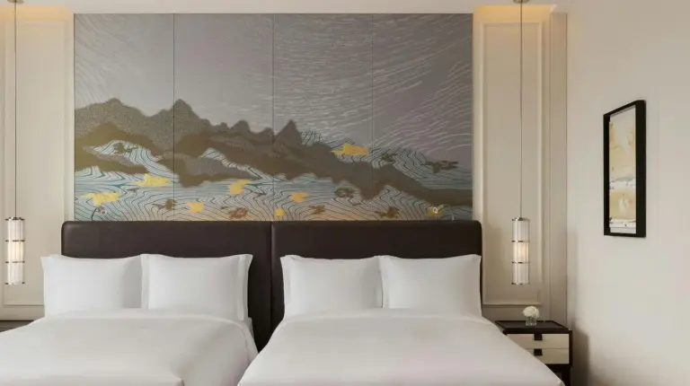 two beds in a hotel room with a painting on the wall at The St. Regis Osaka in Osaka