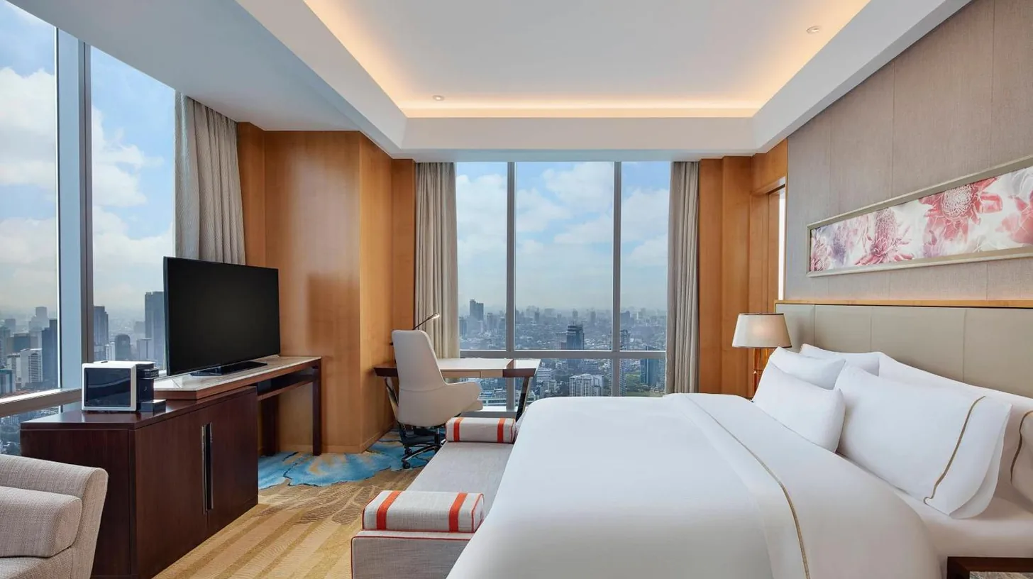 a hotel room with a bed and a desk with a television at The Westin Jakarta in Jakarta