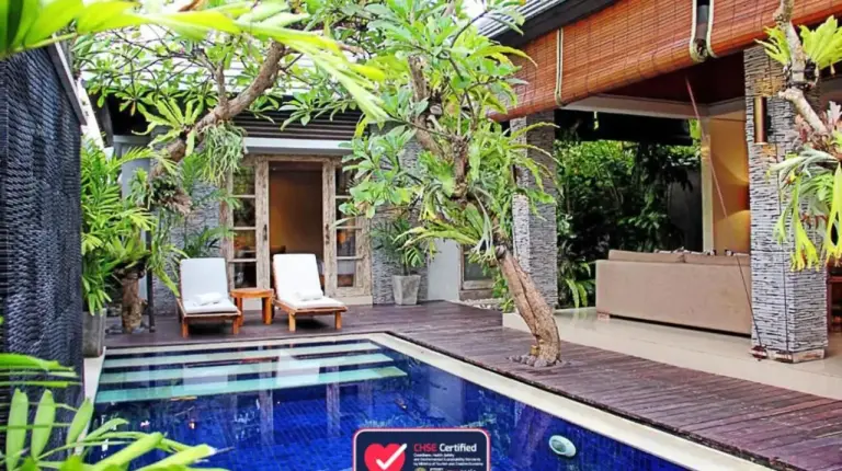a swimming pool in front of a house at The Wolas Villas in Seminyak