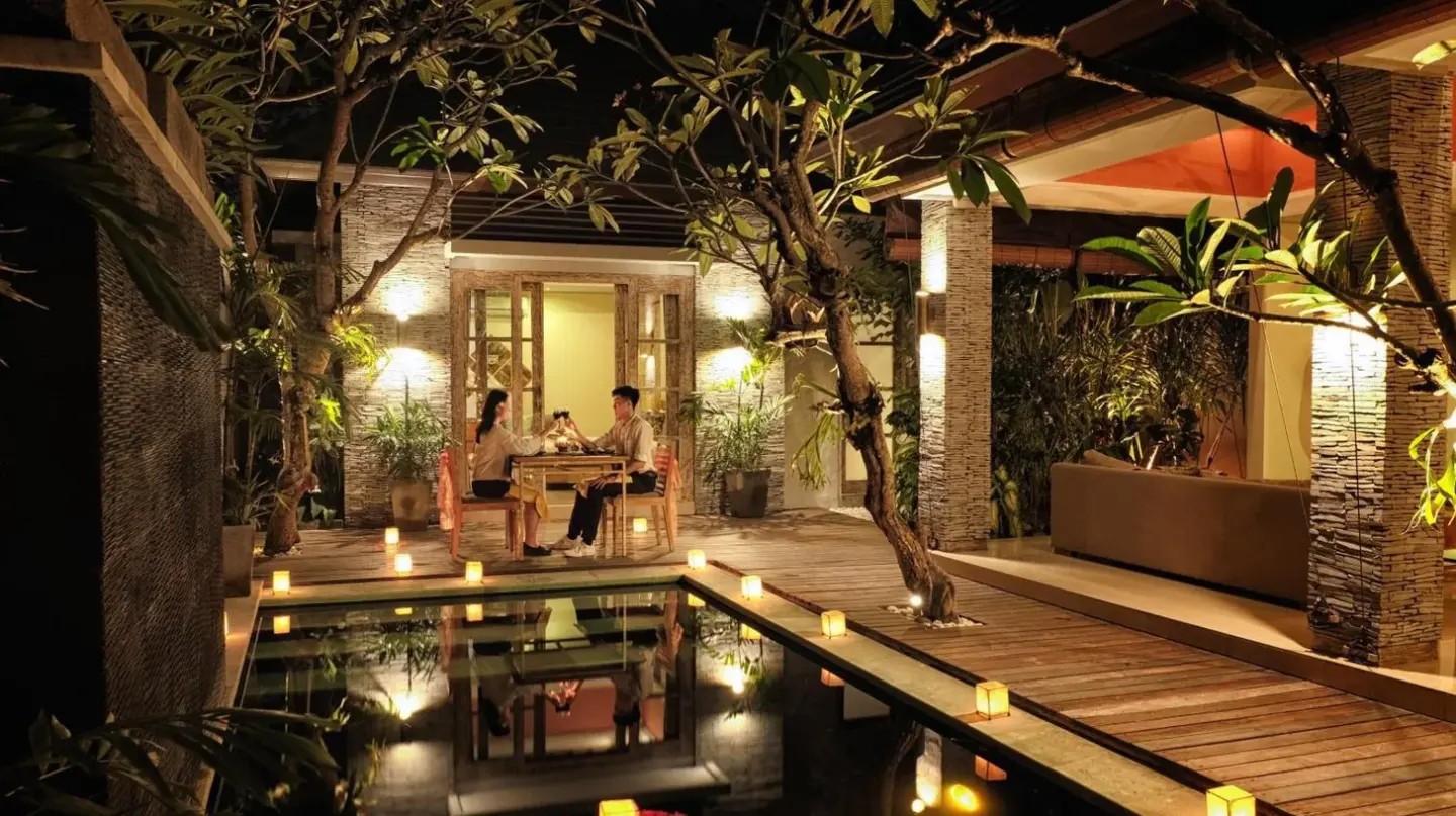 a pool in a house with people sitting at a table at The Wolas Villas in Seminyak
