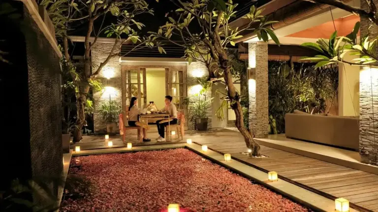 a patio at night with candles and people sitting at a table at The Wolas Villas in Seminyak
