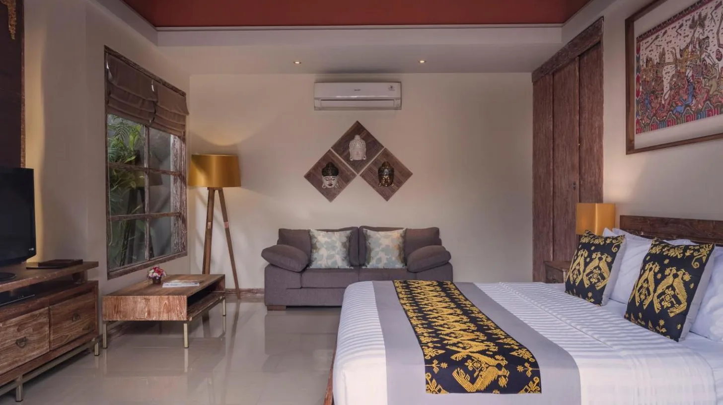 a bedroom with a large bed and a couch at The Wolas Villas in Seminyak
