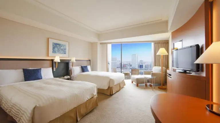 a hotel room with two beds and a table and chairs at The Yokohama Bay Hotel Tokyu in Yokohama