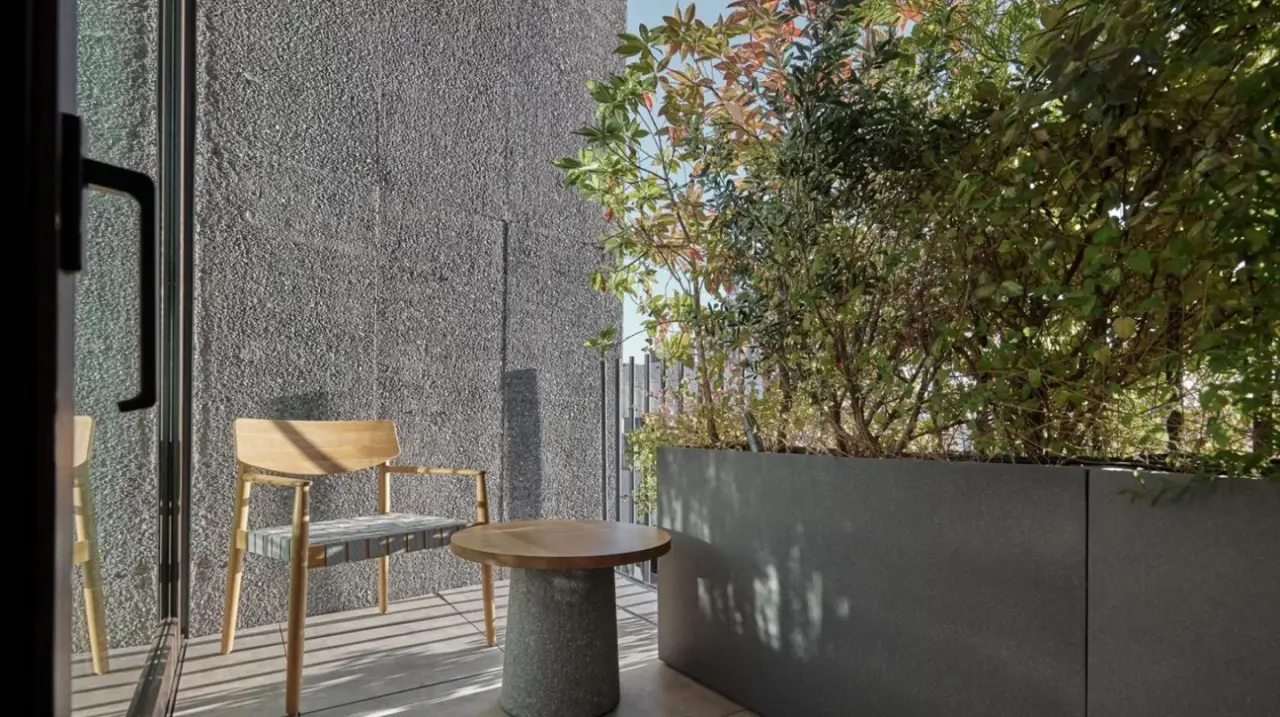a patio with two chairs and a table and a wall at TRUNK(HOTEL) YOYOGI PARK in Tokyo
