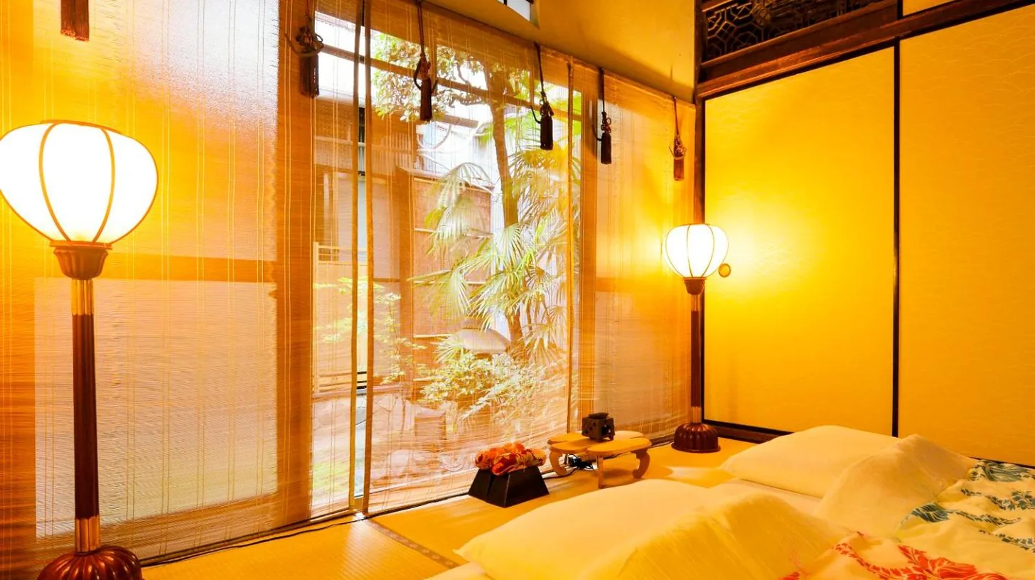 a bedroom with yellow walls and a bed and a window at Udatsuya in Osaka