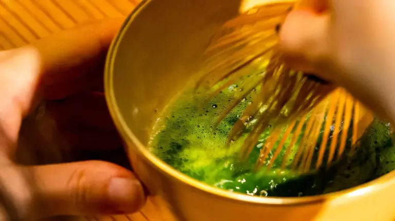a person is stirring a bowl with a whisk at Udatsuya in Osaka