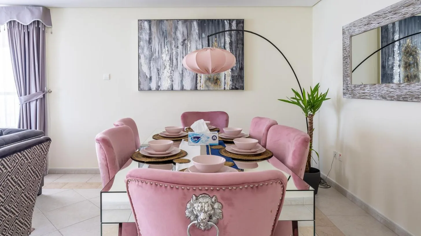 un comedor con una mesa y sillas rosas en Veer Apartments - 82nd Floor Princess Tower - Palm View en Dubái