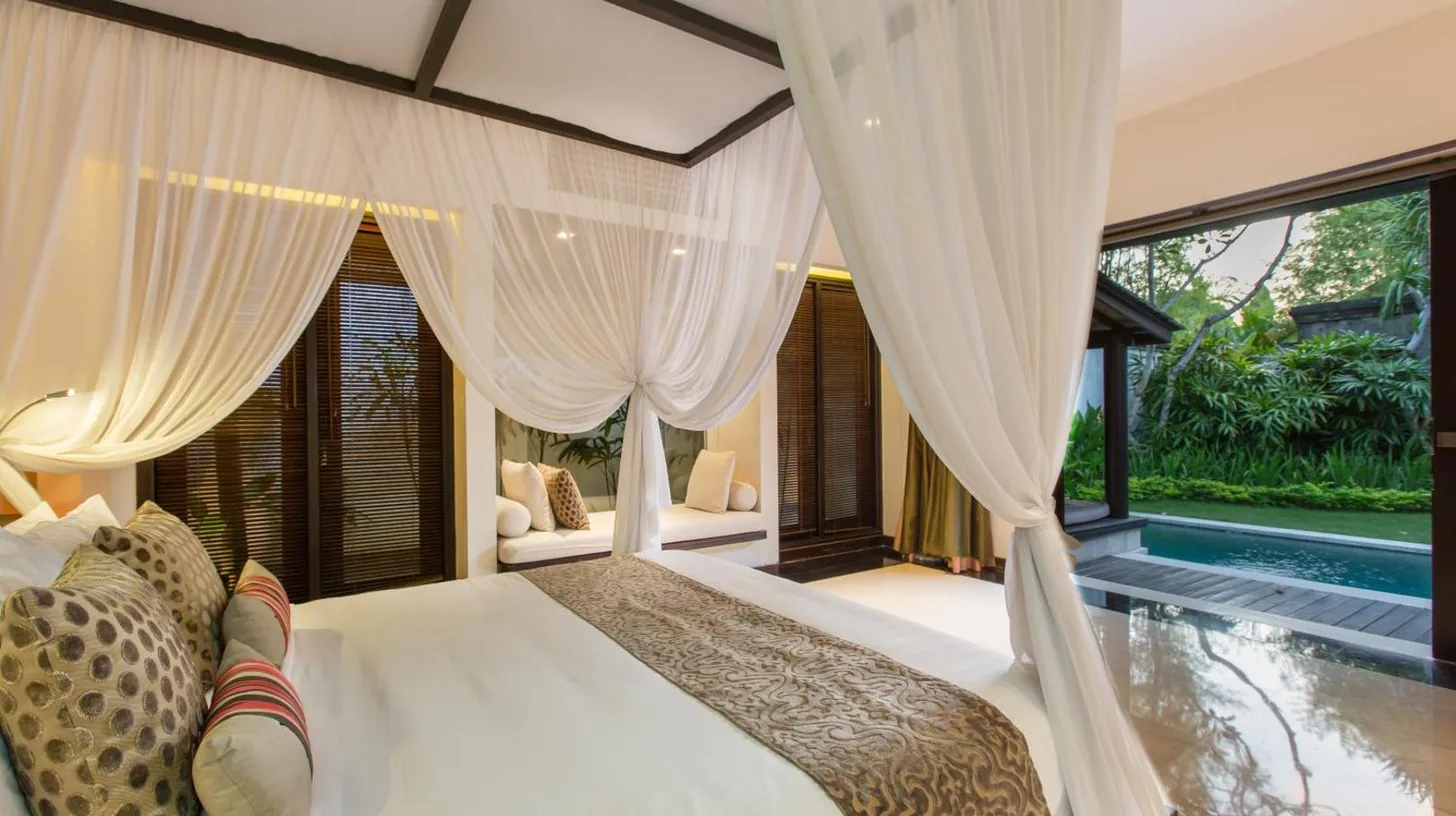 un dormitorio con cama con cortinas y piscina en Villa Air Bali Boutique Resort and Spa en Seminyak
