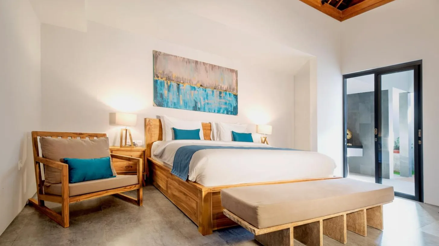 a bedroom with a large bed and a chair at Villa DeDayuh Seminyak in Seminyak