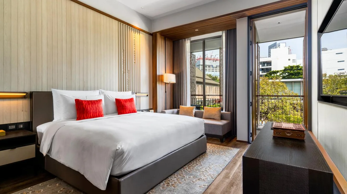 a bedroom with a large bed with red pillows at Villa Deva Resort & Hotel Bangkok in Bangkok