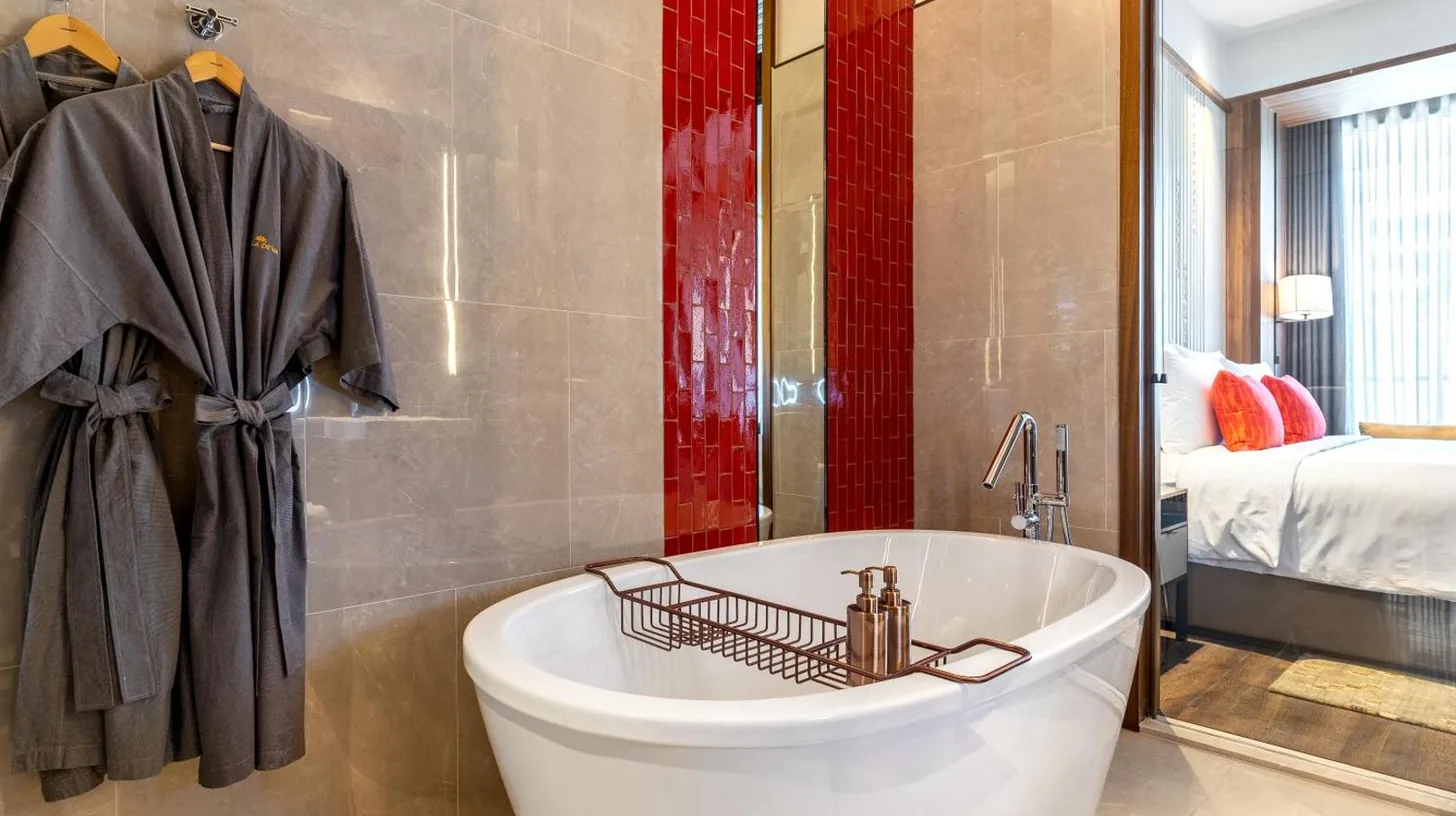 a bathroom with a white tub and a bedroom at Villa Deva Resort & Hotel Bangkok in Bangkok