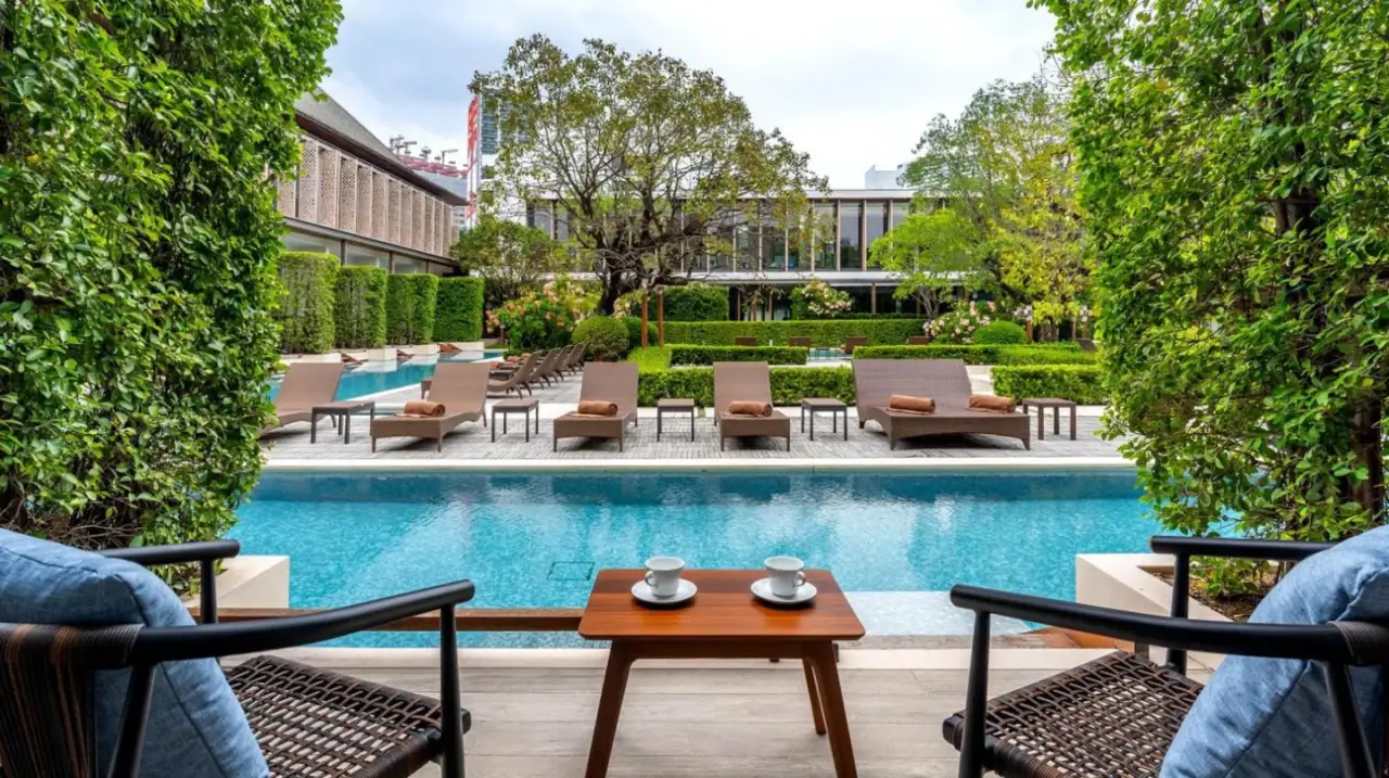 a patio with chairs and a table next to a pool at Villa Deva Resort & Hotel Bangkok in Bangkok