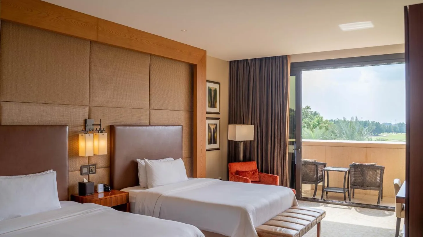 a hotel room with two beds and a balcony at VOGO Abu Dhabi Golf Resort & Spa in Abu Dhabi