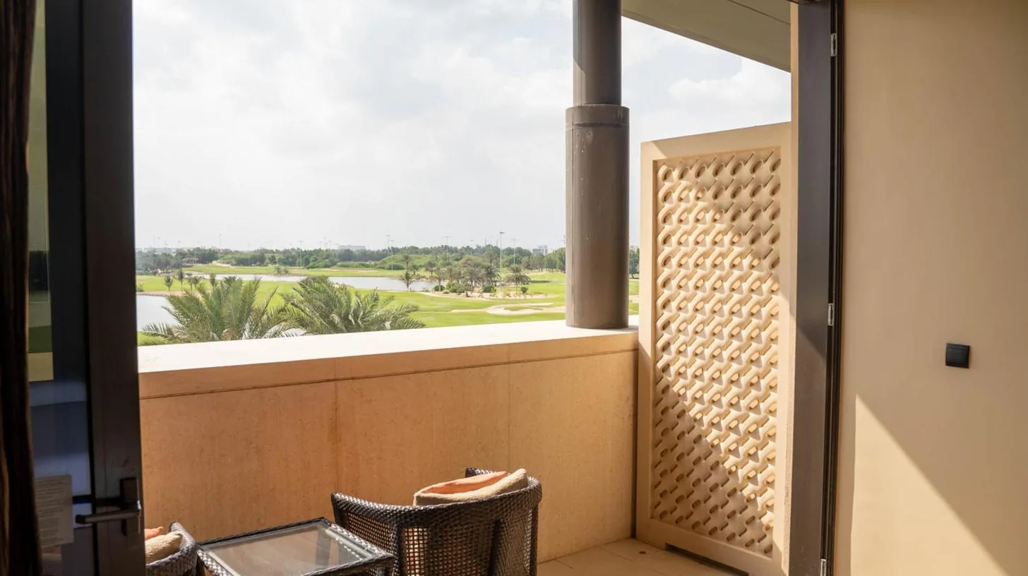 a balcony with a window and a table and chairs at VOGO Abu Dhabi Golf Resort & Spa in Abu Dhabi