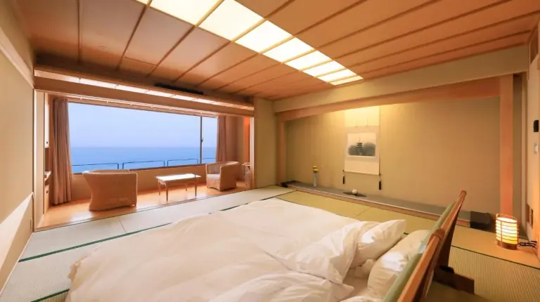 un grand lit dans une chambre avec une grande fenêtre au Wakamatsu Hot Spring Resort à Hakodate