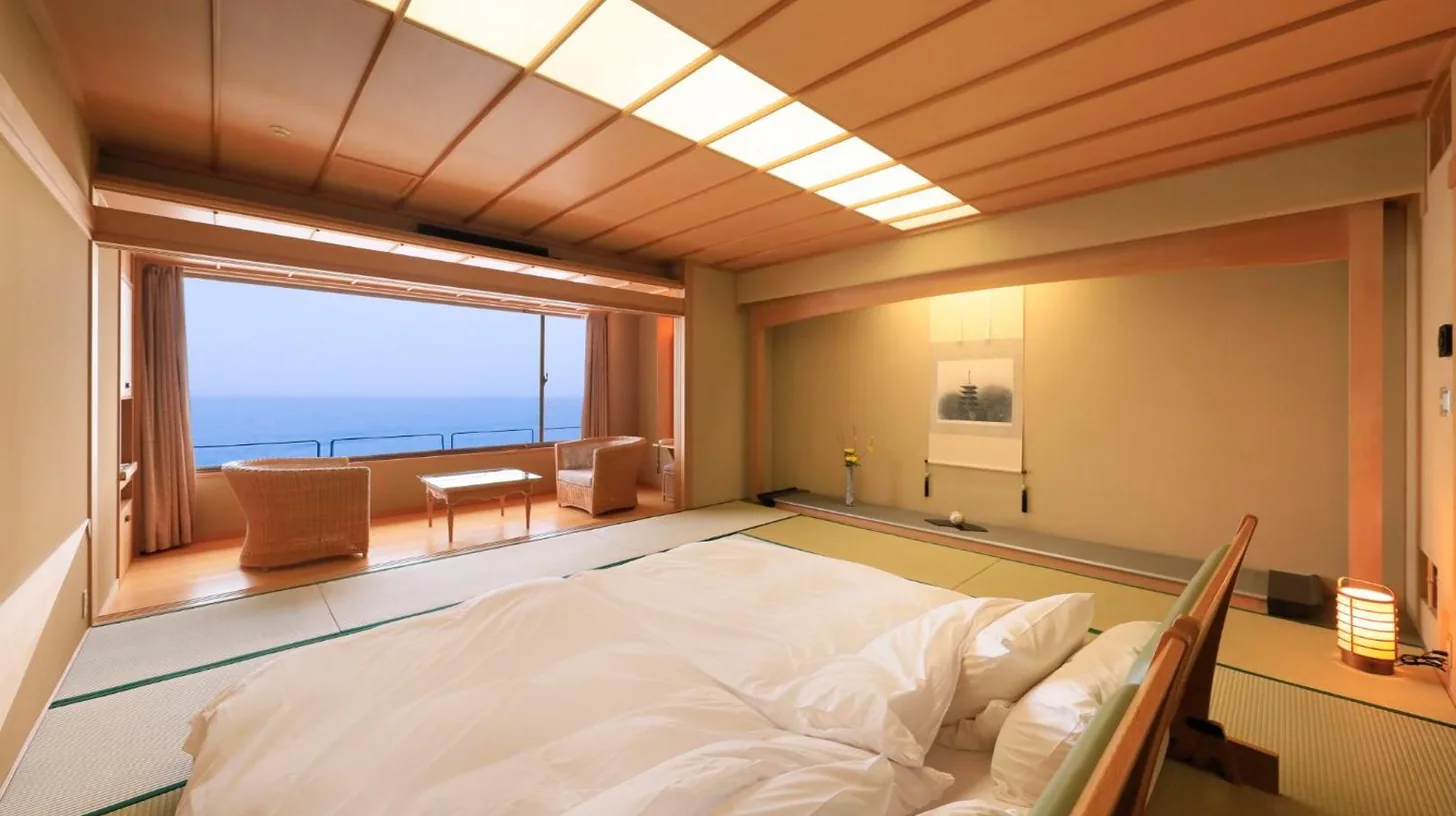 un grand lit dans une chambre avec une grande fenêtre au Wakamatsu Hot Spring Resort à Hakodate