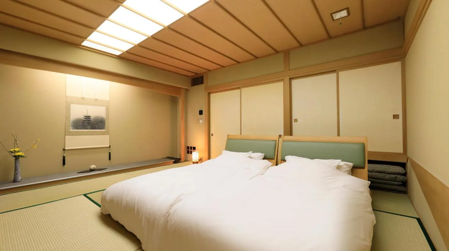 une chambre avec un grand lit blanc et un puits de lumière au Wakamatsu Hot Spring Resort à Hakodate