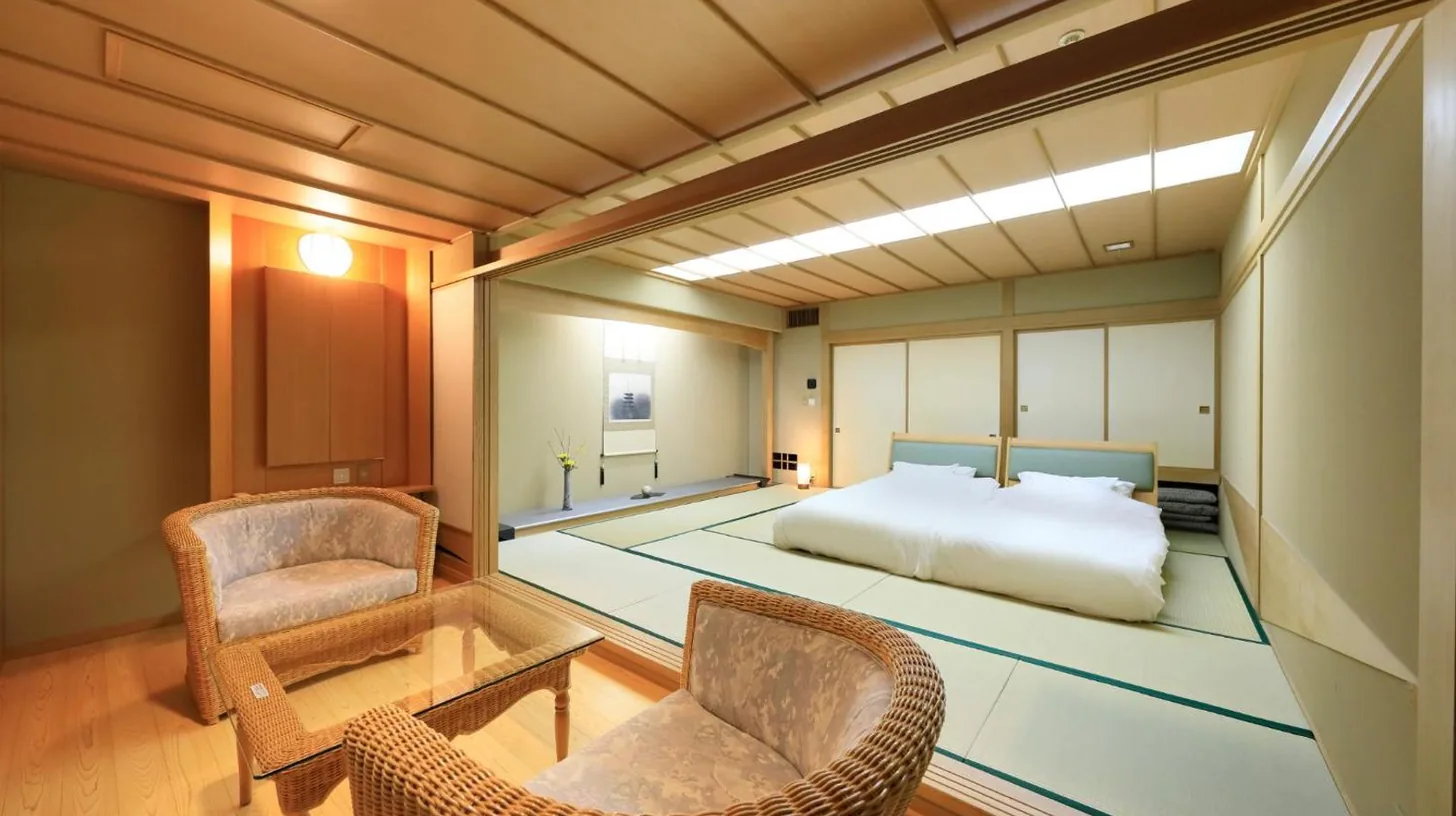 une chambre avec un lit et une table et des chaises au Wakamatsu Hot Spring Resort à Hakodate